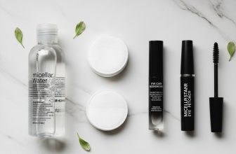 Flat lay of best eye makeup removers, cotton pads, and mascara on a marble vanity.